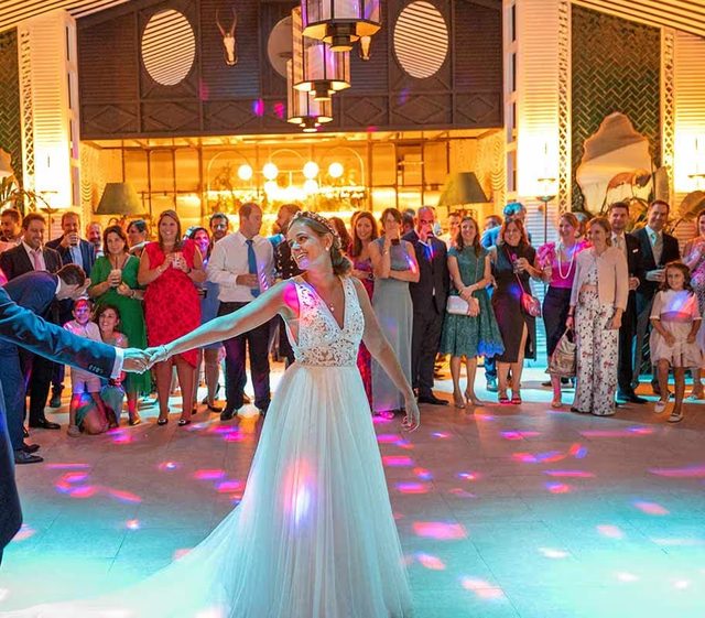 Primer baile de los novios, rodeados de invitados y luces de colores