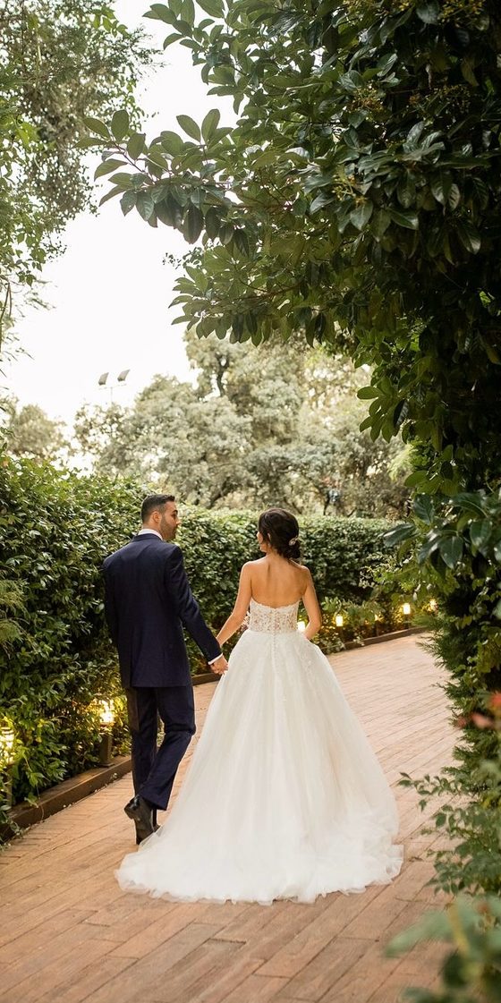 Los novios paseando de espaldas por el jardín