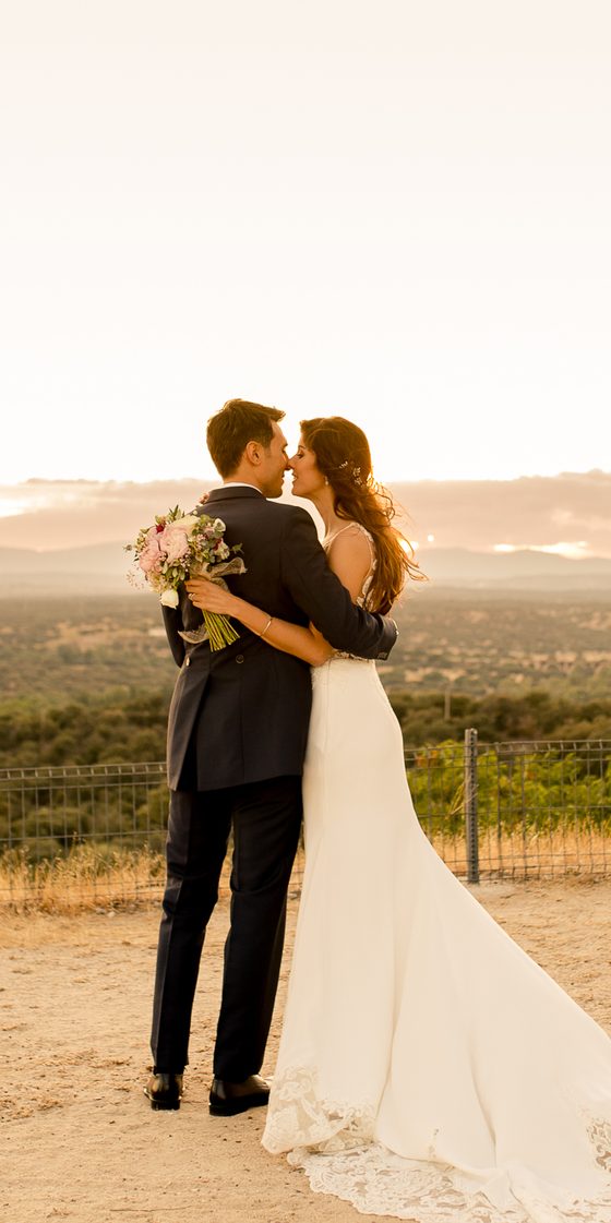 Los novios abrazados al atardecer, con el monte al fondo