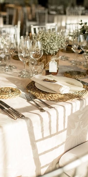 Mesa vestida con bajoplatos de fibra, cristalería y paniculata