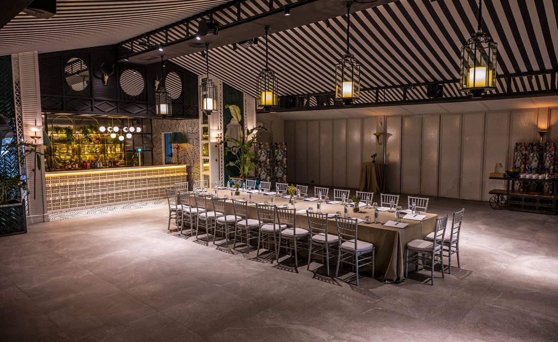 Mesa imperial montada en el Colonial, con la barra iluminada al fondo