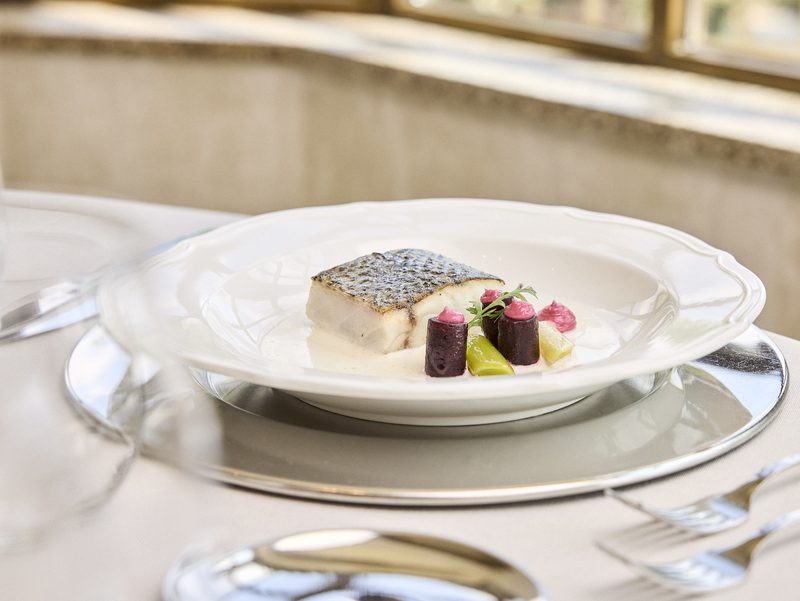 Pescado con costra y guarnición de remolacha, en vajilla clásica