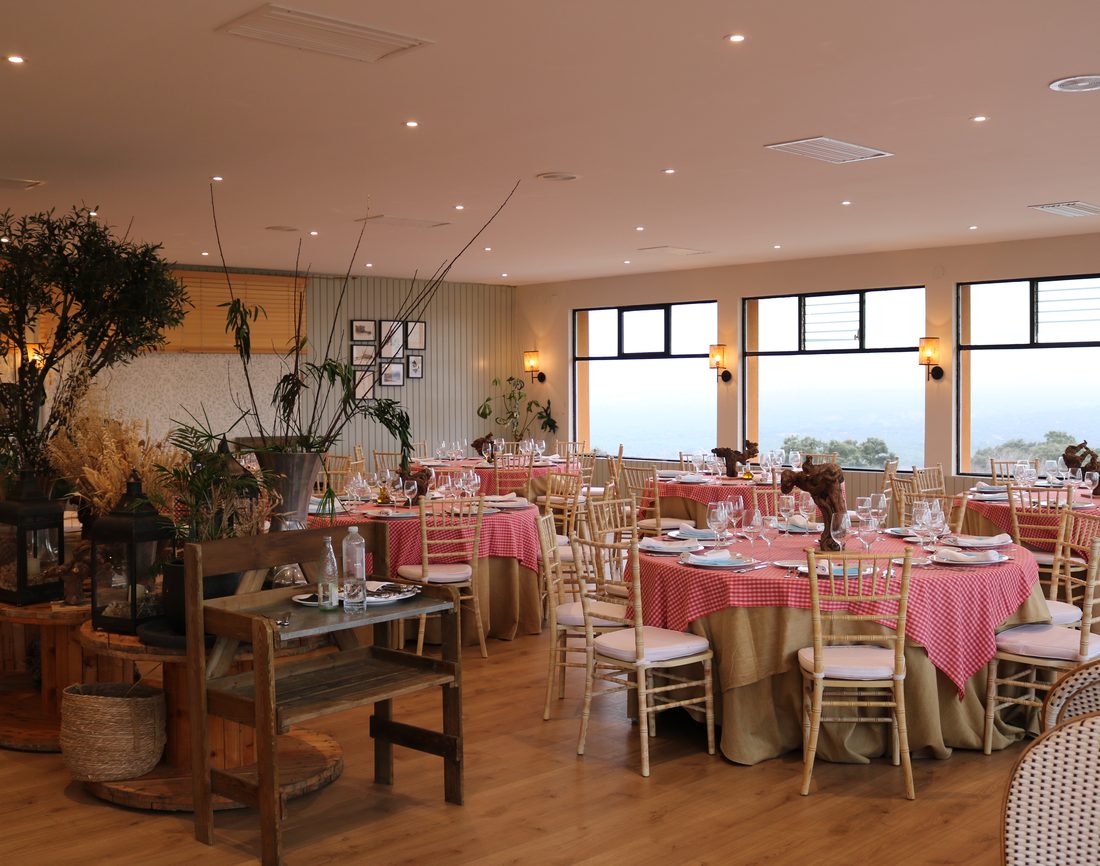 Comedor con mesas vestidas y ventanales al monte