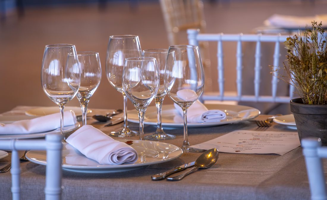 Detalle de la mesa: cristalería y servilleta sobre mantel gris