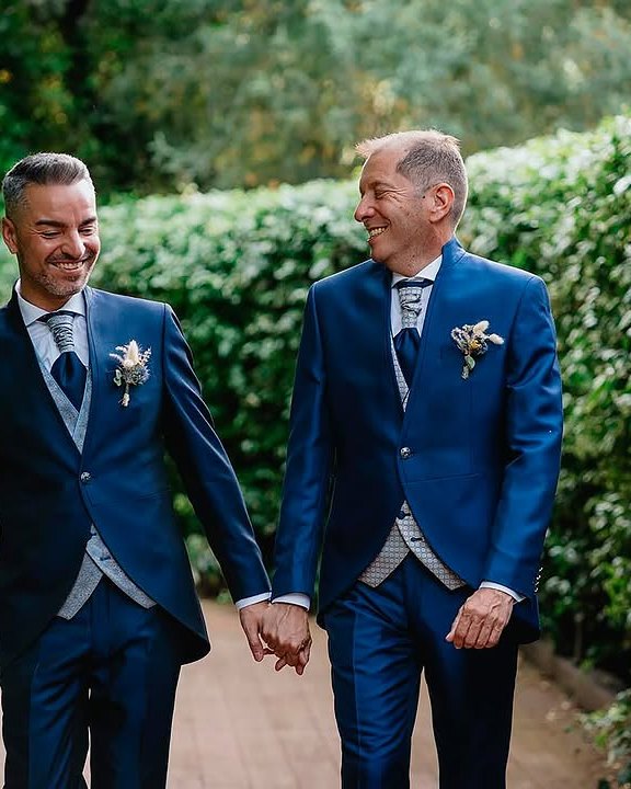 Dos novios de la mano entre los setos